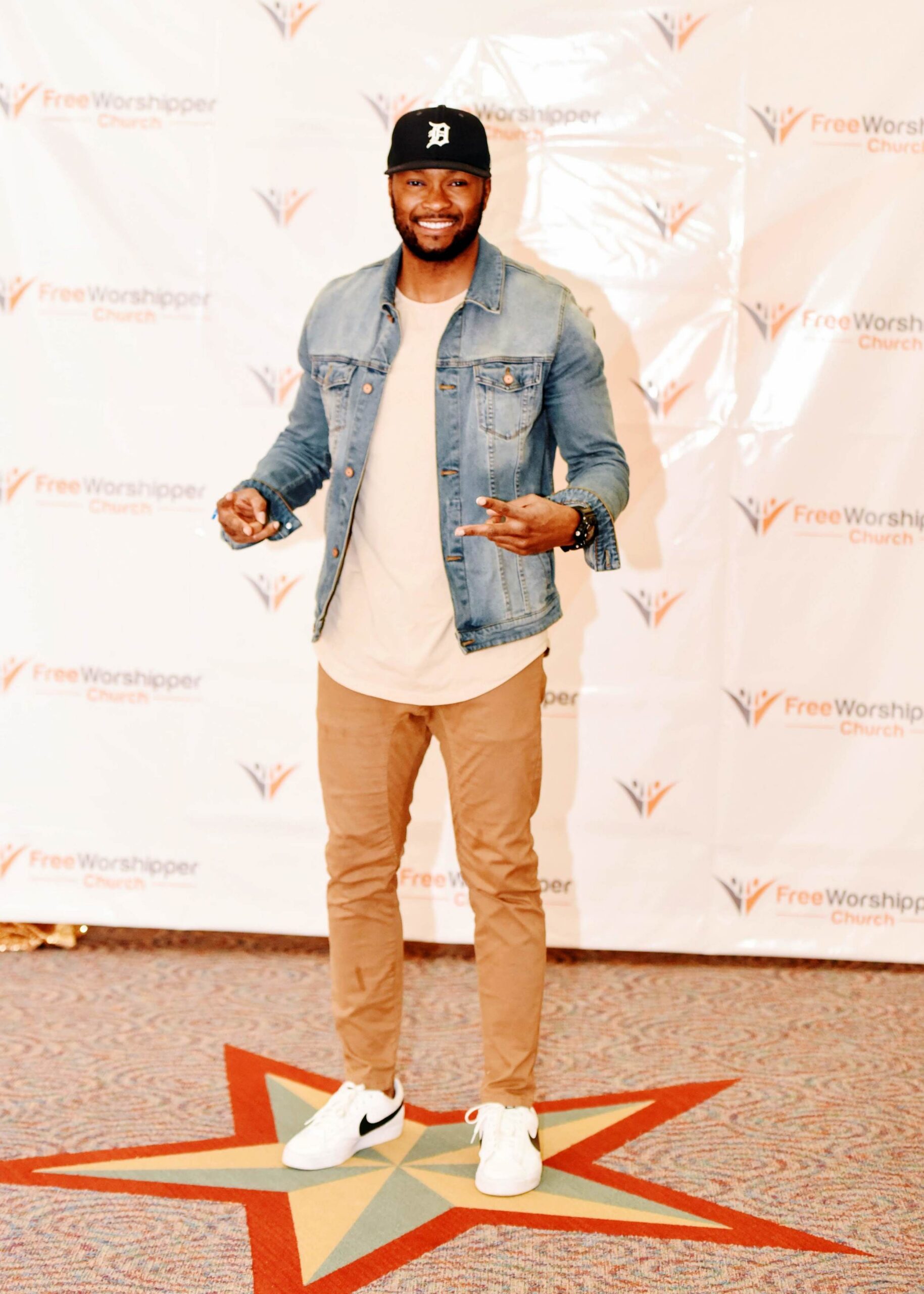 Man posing in front of Free Worshipper Church backdrop