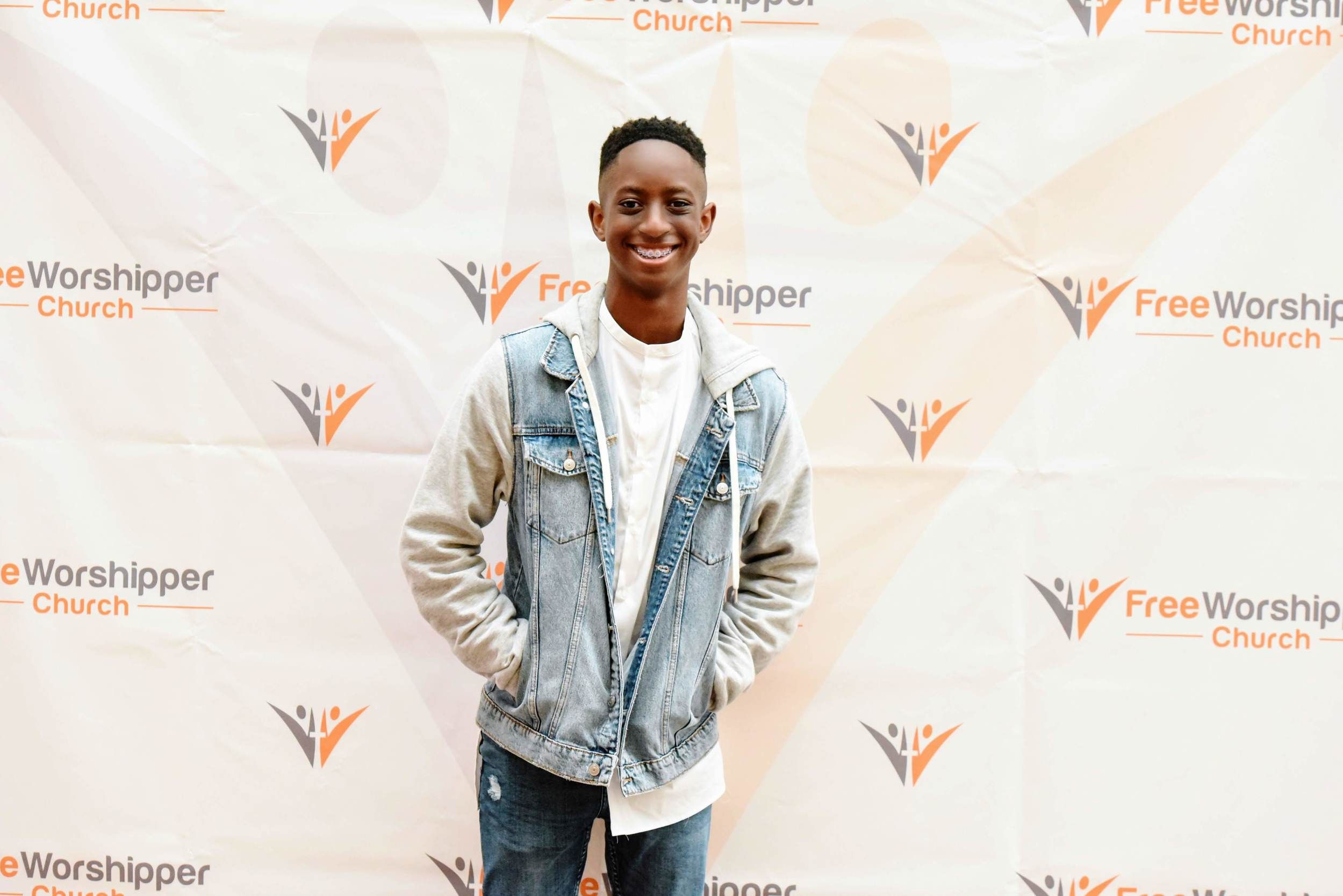 Young man smiling at a church event backdrop