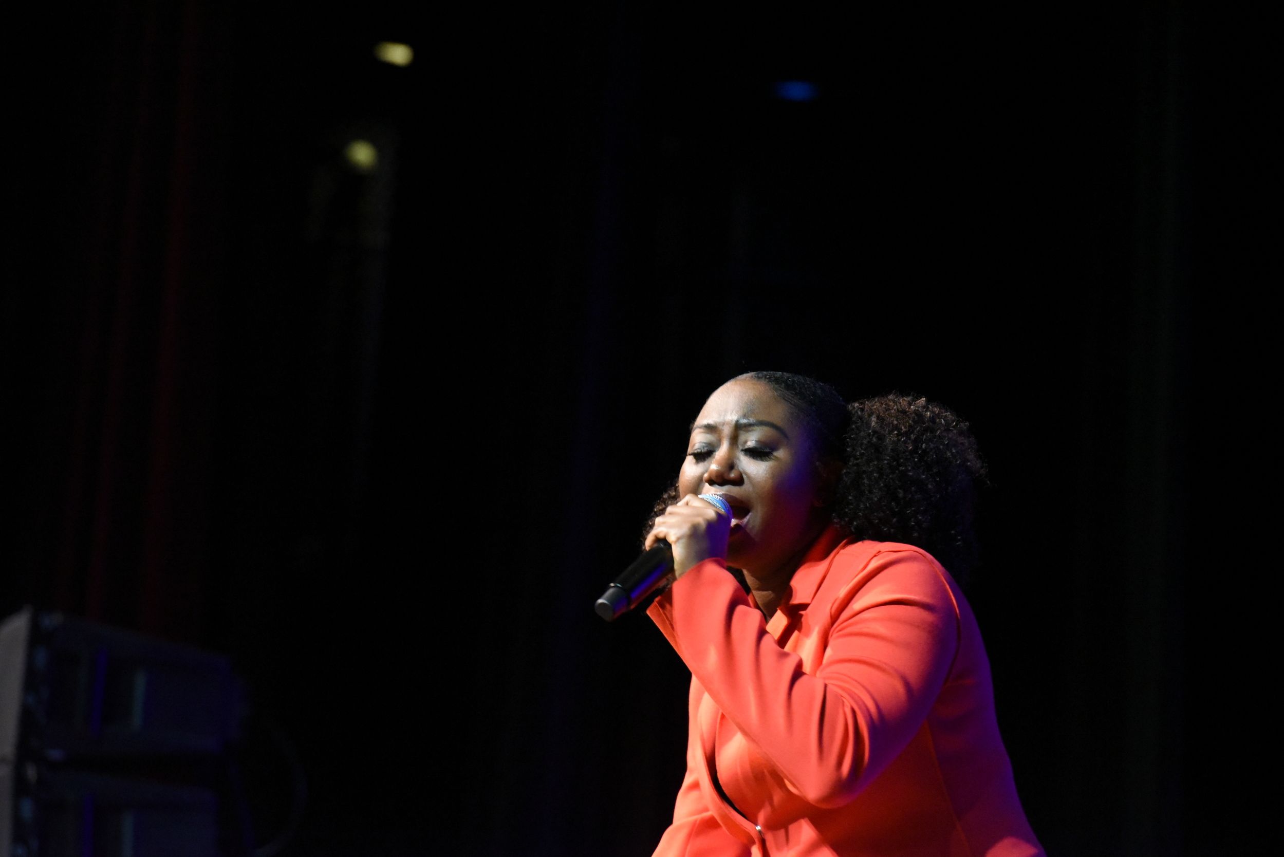Woman singing on stage in coral outfit