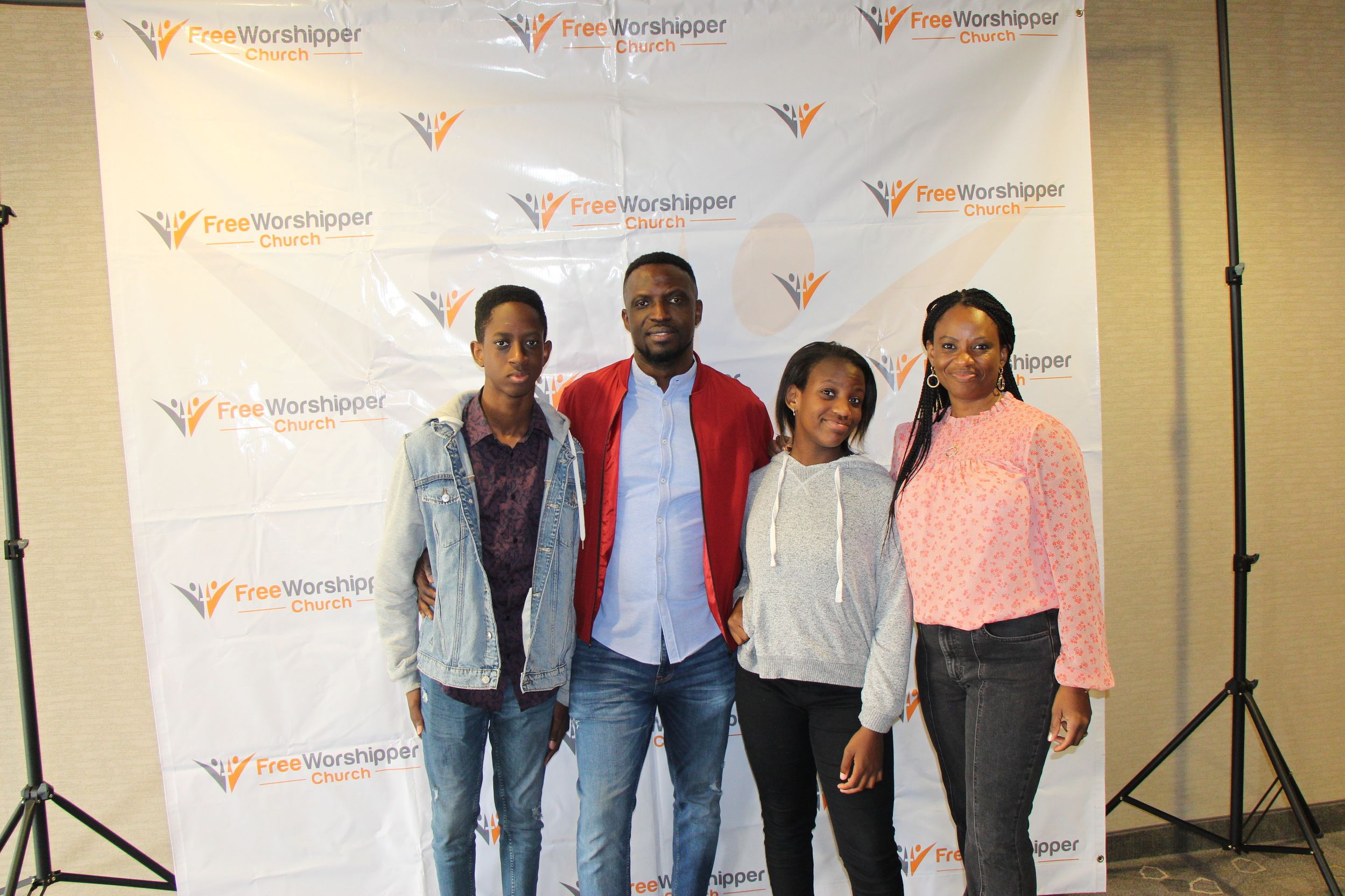 Five church members posing in front of a Free Worshipper Church backdrop