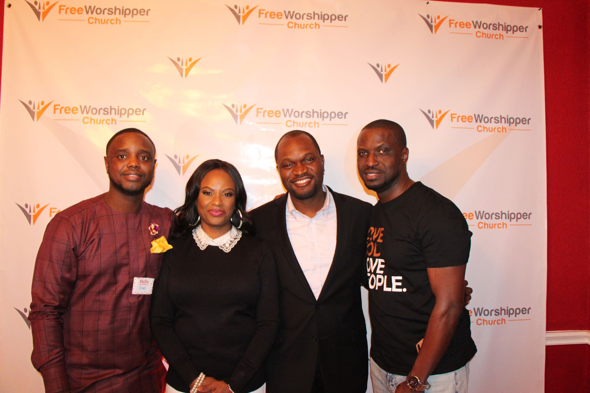 Four church guests posing together at the Free Worshipper Church backdrop