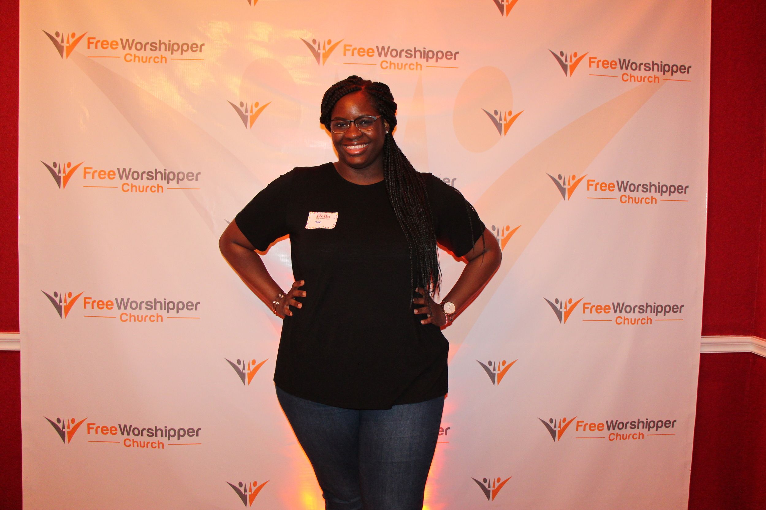 Church guest posing in front of the Free Worshipper Church step-and-repeat backdrop