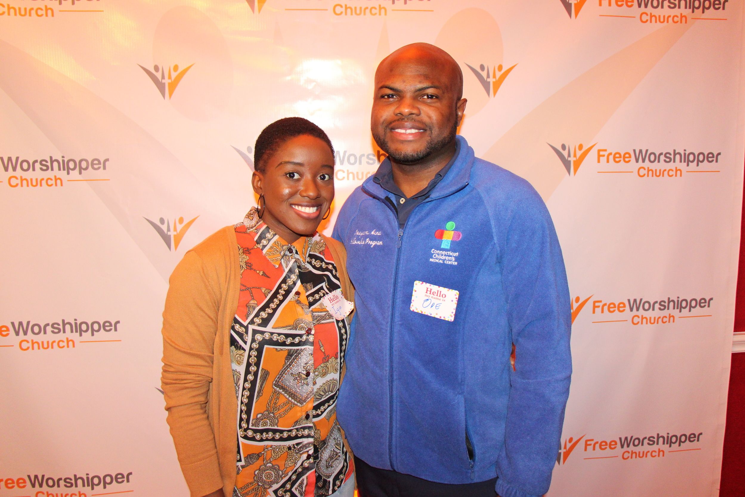 Two smiling guests posing at a Free Worshipper Church community event